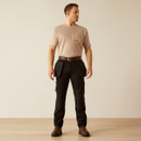 Front full-body view of a male model wearing black utility work pants with detachable tool pouches, a tan T-shirt, belt, and brown work boots against a light studio background.