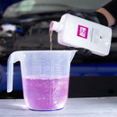 Gloved hand pours pink Autoglym Ultimate Screenwash concentrate into a clear measuring jug to dilute before use.