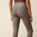 A person wearing high-waisted, textured grey leggings, shown from the back. The leggings have subtle patterns and the background is plain beige.