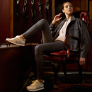 Woman in equestrian attire sits confidently in a leather chair, surrounded by bridles on the wall. She exudes a poised, elegant demeanour.