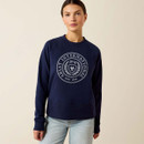 A person stands facing forward, wearing a navy sweatshirt with "Ariat International" and a crest on the front. The tone is casual and confident.