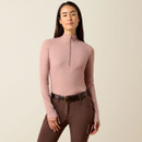 Woman wearing a fitted mauve long-sleeve top with a half-zip, paired with brown riding pants and a belt, exudes a confident and relaxed demeanour.