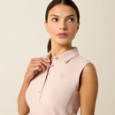 Woman wearing a sleeveless pink polo shirt gazes to the side. Her expression is thoughtful. The shirt features buttons and a small embroidered logo.