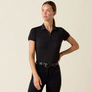 A woman in a sleek black outfit poses confidently against a neutral background. She wears a collared, short-sleeve top and fitted pants, exuding elegance and poise.