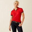 A person wearing a red polo shirt with navy trim and dark jeans, standing confidently against a neutral background. The mood is casual and stylish.