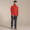 A man wearing a dark orange quarter neck fleece with grey walking trousers and walking boots.