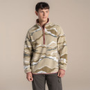 Male model standing in a studio wearing a patterned Craghoppers half-zip  fleece in beige and olive tones, paired with dark walking trousers.