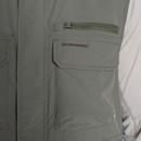 Close-up of dark sage Craghoppers gilet chest pockets, featuring a zipped pocket above a flap pocket with embroidered logo.