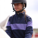 Close-up of the navy and lilac Aubrion Equestrian fleece showing the embroidered logo and zip neck, worn with a black riding helmet.
