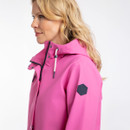 Side profile of model wearing the bright pink hooded rain jacket, showing the sleeve logo patch and high collar.