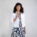 Full-length view of model wearing a white canvas jacket over a navy-and-white patterned dress against a studio backdrop.
