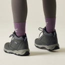 Back view of a person wearing grey mid-cut hiking boots with padded collars and chunky treaded soles.