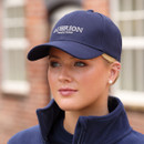 Woman wearing a navy Aubrion Equestrian baseball cap with embroidered logo, outdoor lifestyle shot.