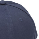 Close-up of the top side of a navy baseball cap showing stitched panel seams and an embroidered ventilation eyelet.