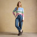 Full-length shot of model wearing pastel striped jumper with blue jeans and cuffed hems, posing against a neutral studio backdrop.