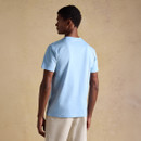 Rear view of a model wearing a light blue short-sleeve T-shirt, showing the clean back design and relaxed fit.
