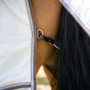 Close-up of a horse's hind covered with a white and gray blanket fastened by a buckle. The horse's dark tail is visible, conveying calmness.
