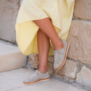 Spotted print lace-up shoes on a model’s feet, featuring white laces, whipstitch detailing and a tan cork-effect midsole by a stone wall.