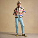 Full-length outfit shot of model wearing light blue chinos with a striped jacket and cap in studio setting.