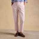 Model wearing pale pink slim-leg chinos with turned-up cuffs, front pockets and button fastening.