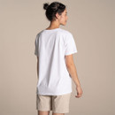 Back view of a women’s plain white short-sleeve T-shirt on model, paired with beige shorts, studio background.