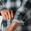 Close-up of the sleeve with adjustable snap-button cuff on the plaid shirt.