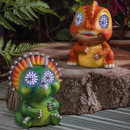 Two cute solar dinosaur garden lights with glowing LED eyes—one green triceratops and one orange T-rex—sitting on a log among plants.
