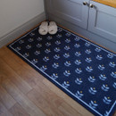 A cosy scene with beige slippers on a navy floral pattern doormat beside grey cabinets on light wood flooring, creating a warm and inviting atmosphere.