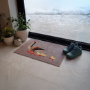 Doormat with geese design near a glass door, flanked by green potted plants. Snowy ground outside, teal hiking shoes nearby indoors. Cosy, wintery feel.