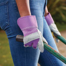 Person wearing purple and grey rigger gloves carrying a garden tool over their shoulder.
