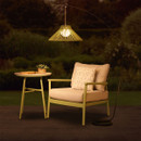 Arched outdoor floor lamp with an illuminated sage green slatted shade, styled beside a patio chair and side table at night.