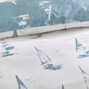 Detailed close-up of the duvet cover fabric showing blue sailing boats and seabirds on a crisp white background.
