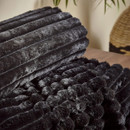 Close-up of a black faux fur throw highlighting soft ribbed stripes and raised bubble detailing.