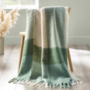 Green and cream check throw blanket draped over a wooden chair with soft fringed edges.