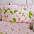Close-up of a ruffled pillowcase featuring a pink strawberry and floral print on a soft pastel background.