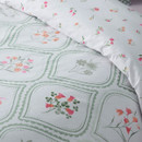 Close-up of reversible bedding fabric featuring delicate pink flowers on a white background
