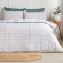 Reversible green and white check duvet cover shown with the lighter reverse side facing up on a neatly made bed.