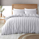 Grey and white striped duvet cover and pillowcases displayed on a neatly made bed in a bright bedroom