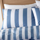 Close-up of a blue and white striped pillowcase on a bed, highlighting the bold vertical stripe design.