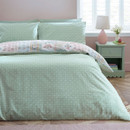 Reversible duvet cover showing the plain sage green patterned side, styled with matching pillowcases on a neatly made bed.