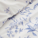 Close-up of the duvet cover fabric showing soft blue floral illustrations and smooth cotton texture.