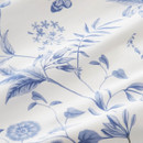 Detailed close-up of white bedding fabric with delicate blue leaves and floral print.