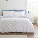Reversible duvet cover showing the white side with scattered blue floral motifs, styled on a neatly made bed.