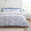 White duvet cover with blue botanical and butterfly print styled on a bed in a bright, airy bedroom.