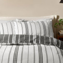 Close-up of striped pillowcases and duvet cover in grey and white, highlighting the clean linear pattern.