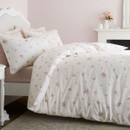 White duvet cover with scattered pink rose print styled on a bed with pale pink cushions and classic headboard.
