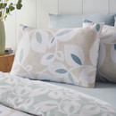 Close-up of leaf print pillowcases in neutral and sage green tones, styled on a bed with coordinating bedding.