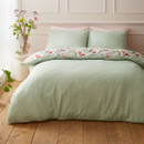 Reversible duvet cover showing the plain sage green patterned side, styled with matching pillowcases on a neatly made bed.