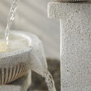 Side detail of the stone-effect structure with water gently pouring between the upper bowls.
