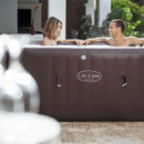 Couple relaxing and talking in a Lay-Z-Spa Maldives inflatable hot tub on a garden patio.
